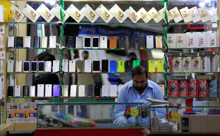 FILE PHOTO: A shopkeeper plays with his mobile phone at a phone market in Rawalpindi, Pakistan July 4, 2017. REUTERS/Caren Firouz/File Photo