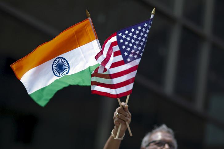 A man holds the flags of India and the U.S. while people take part in the 35th India Day Parade in New York August 16, 2015. REUTERS/Eduardo Munoz