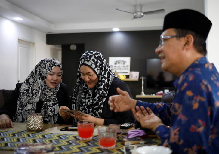 Tengku Shawal, a royal descendant, talks as his daughter Tengku Puteri (L) and his sister Tengku Intan (C) reminisce over old family photos at Intan's home in Singapore August 21, 2020. Picture taken August 21, 2020. REUTERS/Edgar Su