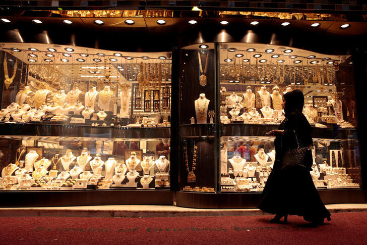 FILE PHOTO: A woman walks past gold jewellery displayed in a shop window at the Gold Souq in Dubai, United Arab Emirates March 24, 2018. REUTERS/Christopher Pike/File Photo