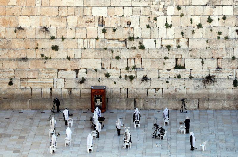 A small number of Jewish worshippers pray during the priestly blessing, a traditional prayer which usually attracts thousands of worshippers at the Western Wall on the holiday of Passover, amid the coronavirus disease (COVID-19) outbreak, in Jerusalem's Old City April 12, 2020 REUTERS/Ronen Zvulun