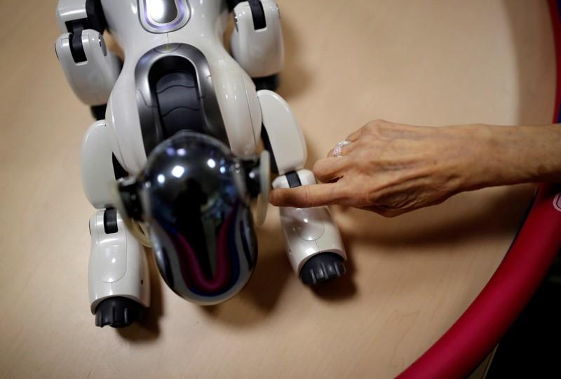 A resident touches 'AIBO', a pet dog robot, at Shin-tomi nursing home in Tokyo, Japan, February 2, 2018. REUTERS/Kim Kyung-Hoon SEARCH 