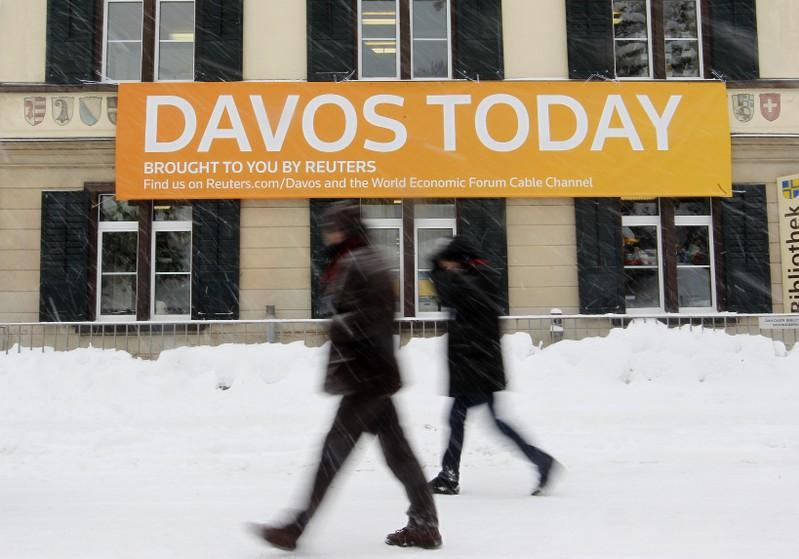 People walk past a banner of Reuters News in front of their office during the World Economic Forum (WEF) at a library in the Swiss mountain resort of Davos January 24, 2012. The upcoming WEF will be held from January 25 to 29. REUTERS/Arnd Wiegmann
