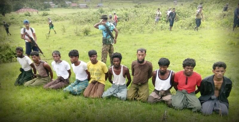 This photo was taken on the day the 10 Rohingya men were killed. Paramilitary police officer Aung Min, left, stands guard behind them. The picture was obtained from a Buddhist village elder, and authenticated by witnesses.