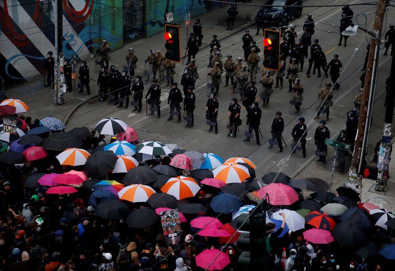 Protesters use umbrellas at the front line of a barricade guarded by Seattle police and the National Guard following the death in Minneapolis police custody of George Floyd, near the department's East Precinct in Seattle, Washington, U.S. June 3, 2020. REUTERS/Lindsey Wasson