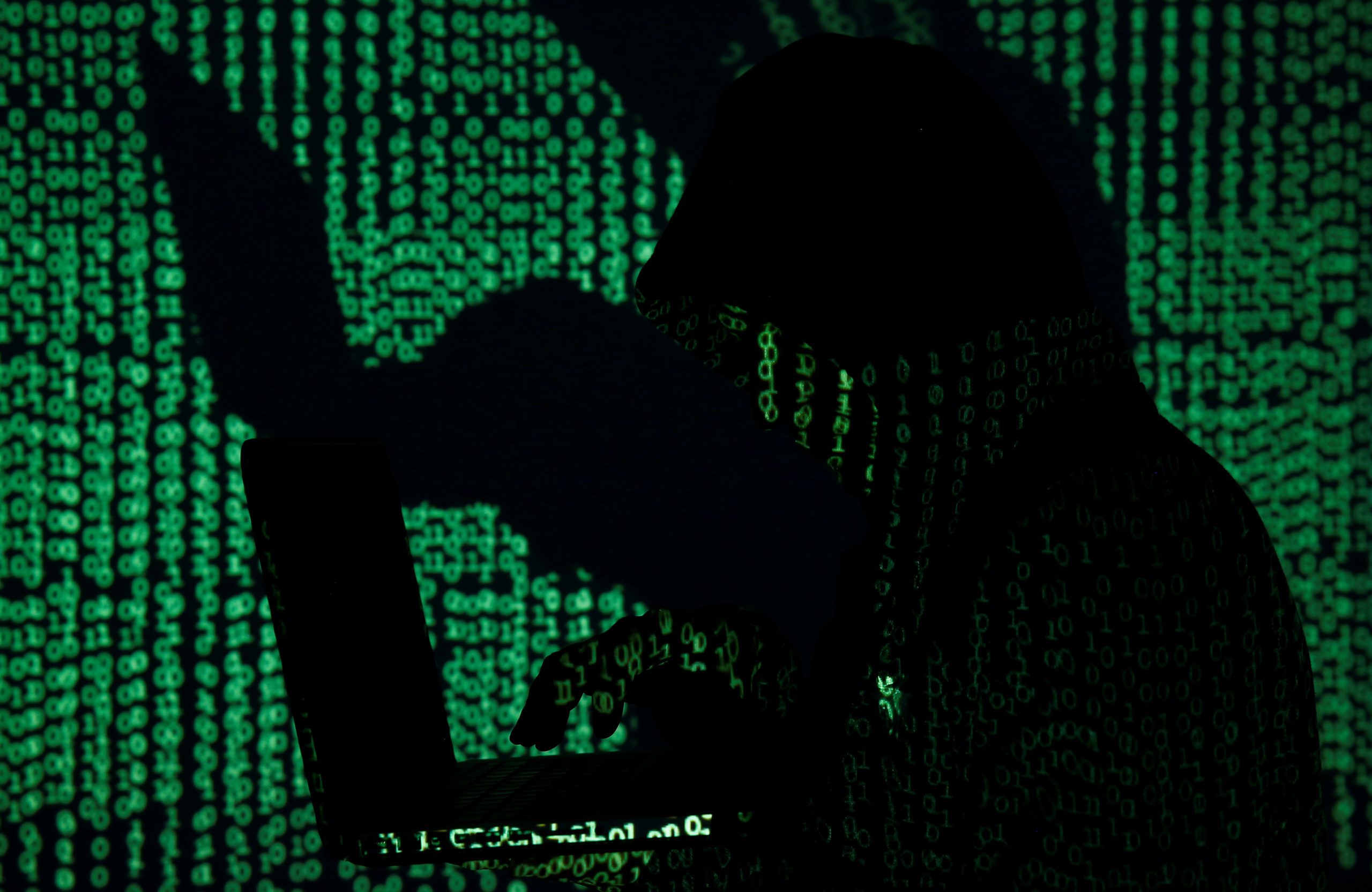 FILE PHOTO: A man holds a laptop computer as cyber code is projected on him in this illustration picture taken on May 13, 2017.  REUTERS/Kacper Pempel/Illustration