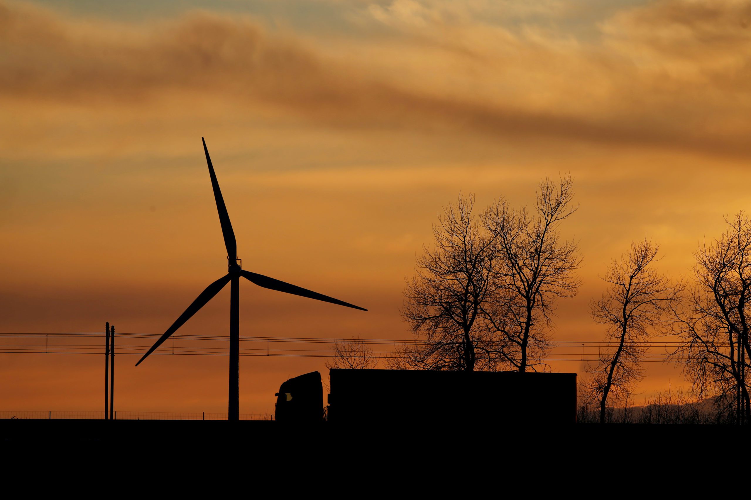 A truck drives in front of a power-generating windmill turbine on the Paris-Lille highway during sunset in Wancourt, France, April 3, 2019. REUTERS/Pascal Rossignol - RC1D3F655480