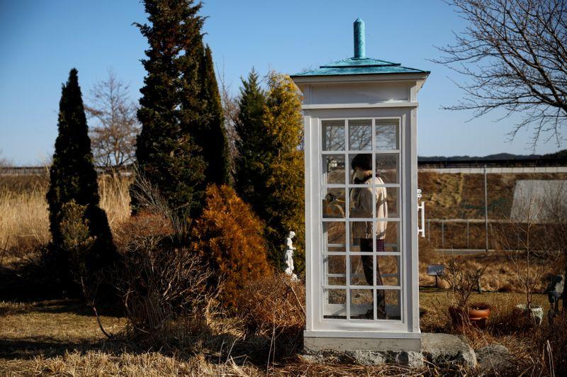 A woman from Ofunato who lost her junior high school classmates in the March 11, 2011 earthquake and tsunami, calls her late friends inside Kaze-no-Denwa (the phone of the wind), a phone booth set up for people to call their deceased loved ones, at Bell Gardia Kujira-yama, ahead of the 10th anniversary of the disaster, in Otsuchi town, Iwate Prefecture, northern Japan February 28, 2021. REUTERS/Issei Kato SEARCH 