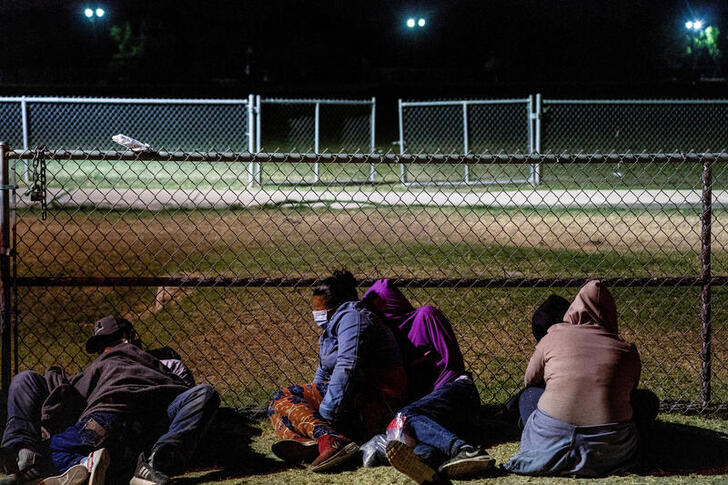 FILE PHOTO: Asylum-seeking migrants' families rest on the ground while waiting to be transported by the U.S. Border Patrols after crossing the Rio Grande River into the United States from Mexico in La Joya, Texas, U.S., April 7, 2021. REUTERS/Go Nakamura/File Photo