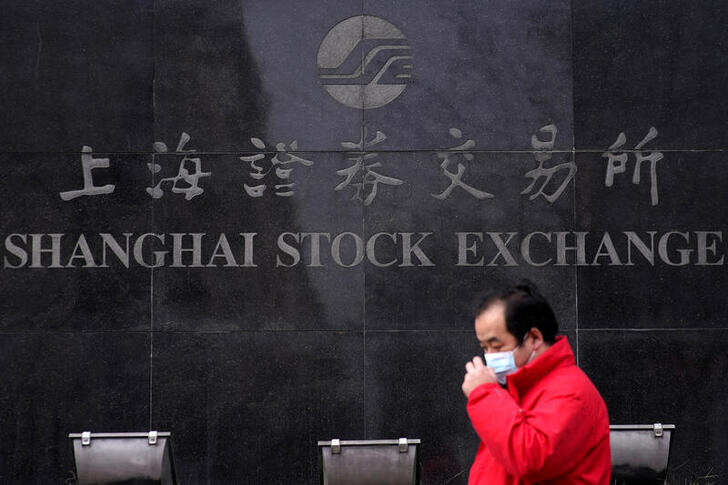 FILE PHOTO: A man wearing a mask walks by the Shanghai Stock Exchange building at the Pudong financial district in Shanghai, China, February 3, 2020. REUTERS/Aly Song/File Photo