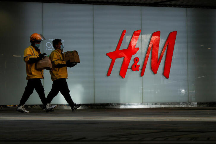 FILE PHOTO: People walk past an H&M store in a shopping area in Beijing, China, March 28, 2021. REUTERS/Thomas Peter/File Photo