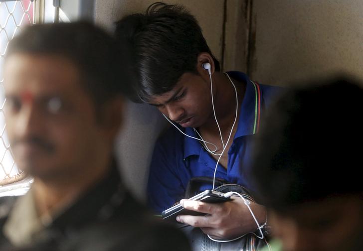 A man watches a video on his mobile phone as he commutes by a suburban train in Mumbai, India, March 31, 2016. With smartphone sales booming and India preparing for nationwide 4G Internet access, India's film and TV industry hopes the ease of tapping your phone for the latest release will generate profits at last, overcoming the problems of woefully few cinemas and rampant piracy. Picture taken March 31, 2016. REUTERS/Shailesh Andrade