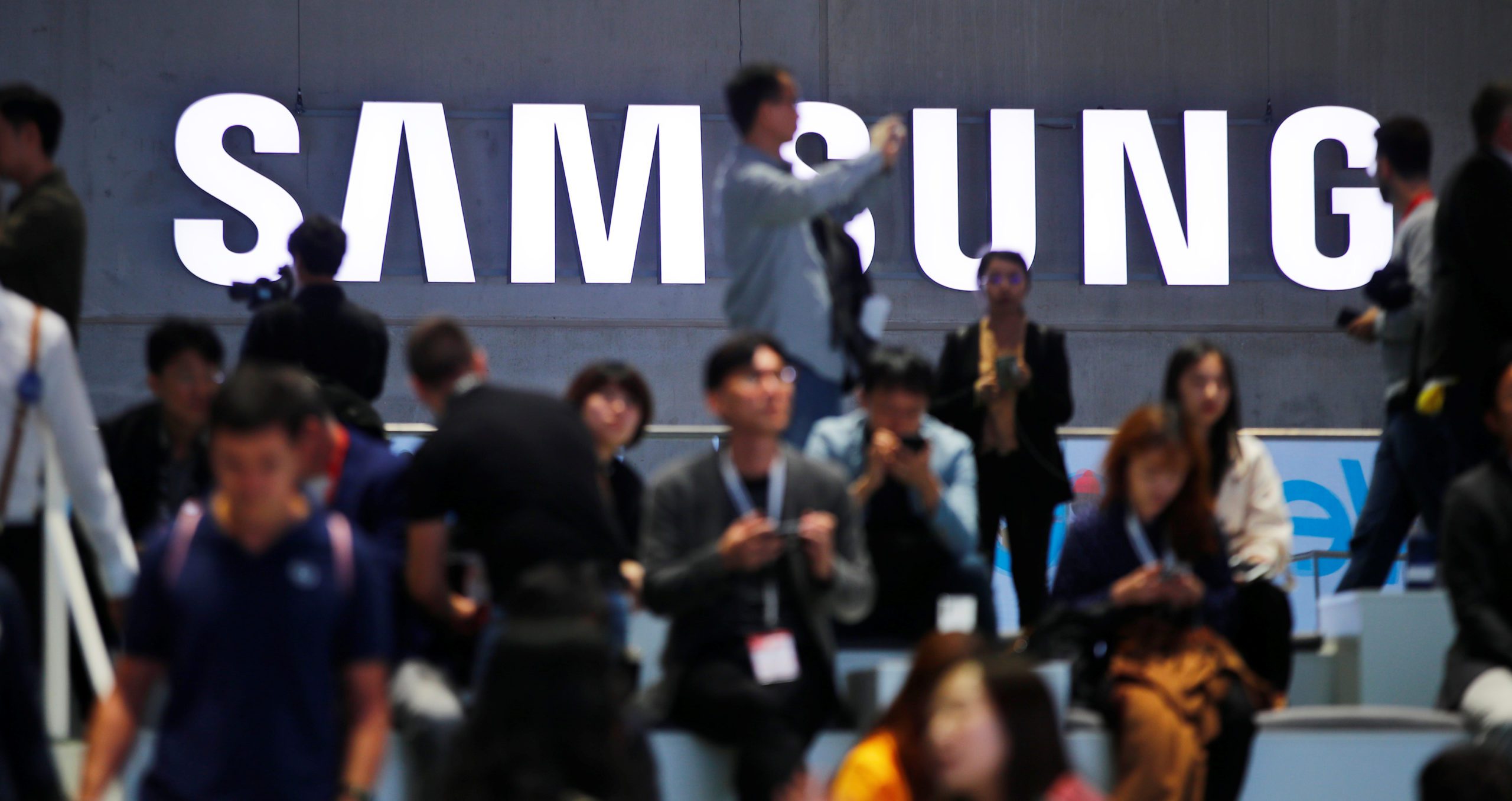 People sit in front of a Samsung logo at the IFA consumer tech fair in Berlin, Germany, September 6, 2019. REUTERS/Hannibal Hanschke - RC1D220499C0