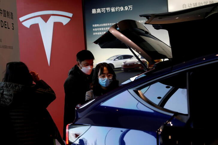FILE PHOTO: Visitors wearing face masks check a China-made Tesla Model Y sport utility vehicle (SUV) at the electric vehicle maker's showroom in Beijing, China January 5, 2021. REUTERS/Tingshu Wang/File Photo