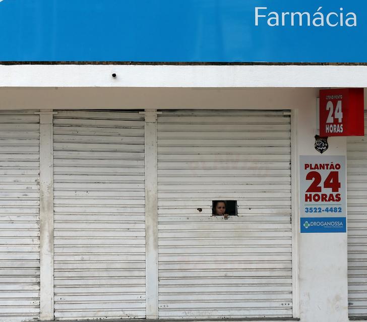 A drugstore vendor looks through a small window in the door of a pharmacy in Cachoeira do Itapemirim, Espirito Santo, Brazil, February 7, 2017. REUTERS/Paulo Whitaker
