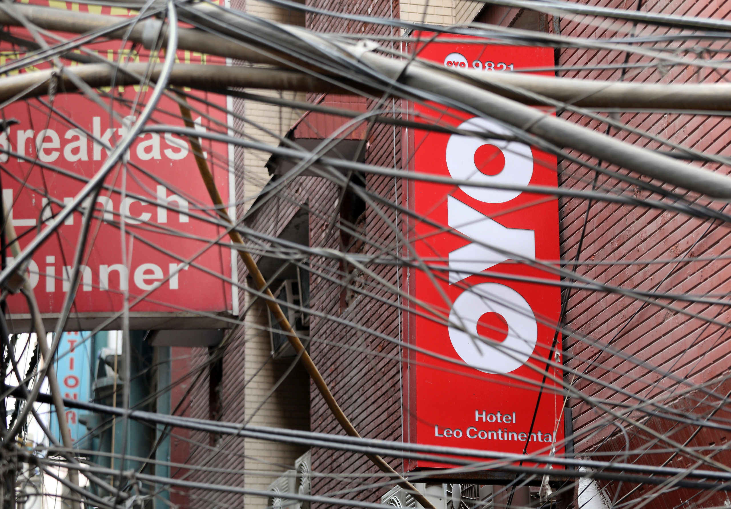 The logo of OYO, India's largest and fastest-growing hotel chain, installed on a hotel building is seen through wires in an alley in New Delhi, India, September 25, 2018. REUTERS/Anushree Fadnavis - RC1364FBCAC0