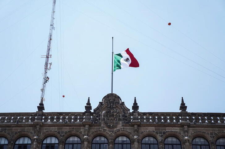A Mexican flag flies at half-staff at the Government House on Constitution Square as a mark of respect for the victims of the accident where an overpass of the metro partially collapsed with train cars on it in Mexico City, Mexico May 4, 2021. REUTERS/Toya Sarno Jordan