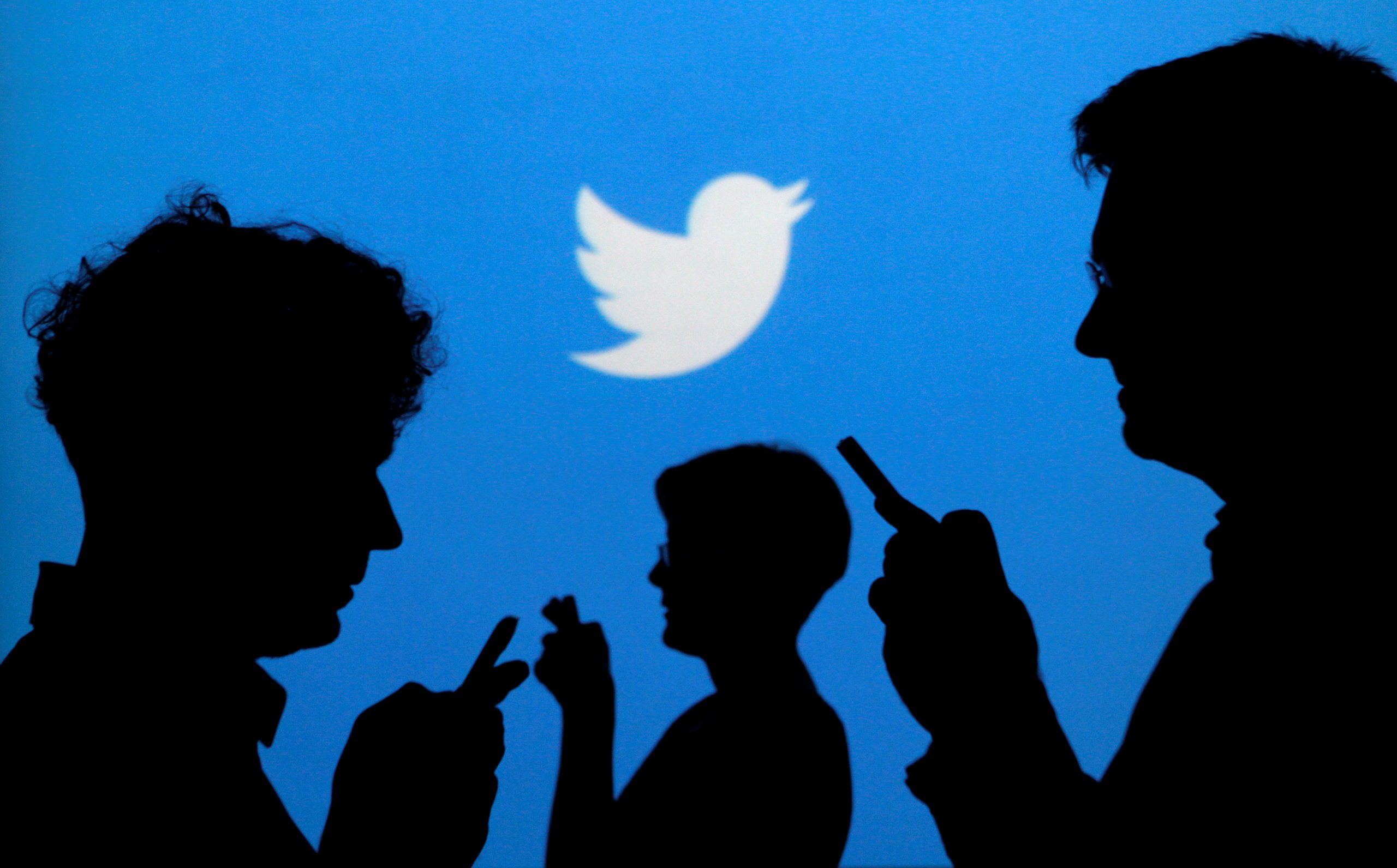 FILE PHOTO: People holding mobile phones are silhouetted against a backdrop projected with the Twitter logo in this illustration picture taken in  Warsaw September 27, 2013.  REUTERS/Kacper Pempel/File Photo - RC2DKO9UQOLM