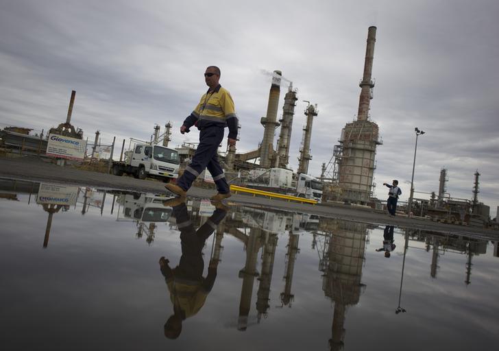 A worker is reflected in a puddle at Sydney's Caltex Oil refinery in Kurnell, October 14, 2014, after the completion of shutting down of the refinery and its transition to an oil storage facility. Brent oil prices fell on Monday, tumbling more than $2 a barrel intraday to their lowest since 2010, after key Middle East producers signaled they would keep output high even if that meant lower prices. Brent oil prices have tanked by nearly 25 percent since June as ample supply coincided with weak demand, raising the possibility that the Organization of the Petroleum Exporting Countries (OPEC) could cut output. REUTERS/Jason Reed (AUSTRALIA - Tags: ENERGY BUSINESS TPX IMAGES OF THE DAY)