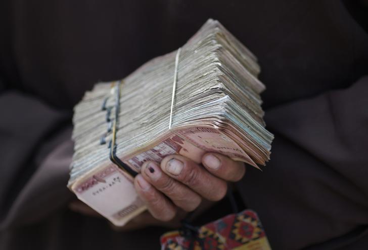 A money changer holds a stack of Afghan currency on a street in central Kabul April 2, 2014. REUTERS/Tim Wimborne  (AFGHANISTAN - Tags: BUSINESS)