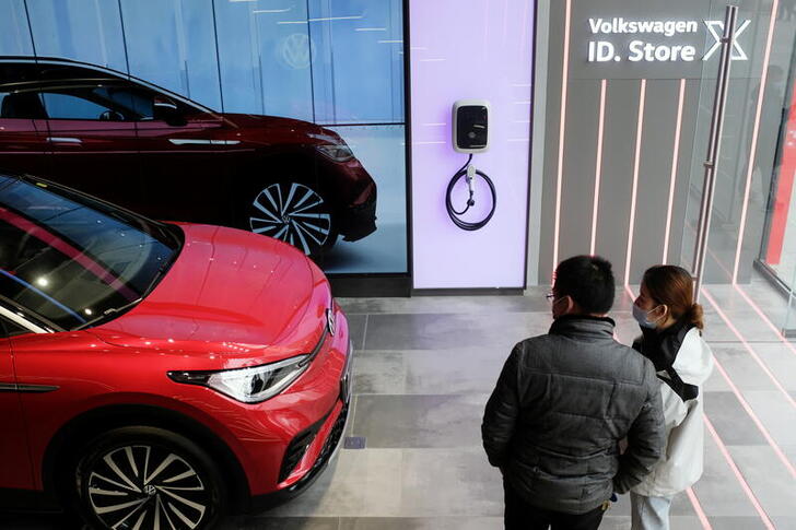 FILE PHOTO: People check a Volkswagen ID.4 X electric vehicle displayed inside an ID. Store X showroom of SAIC Volkswagen in Chengdu, Sichuan province, China January 10, 2021. REUTERS/Yilei Sun/File Photo