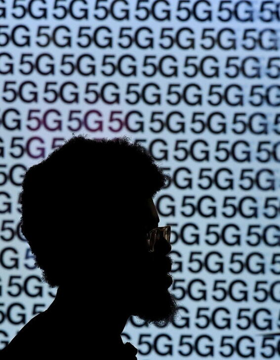 FILE PHOTO: A man walks past an advertisement promoting the 5G data network at a mobile phone store in London, Britain, January 28, 2020. REUTERS/Toby Melville/File Photo