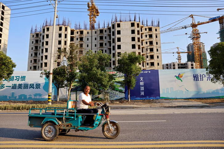 FILE PHOTO: A man rides a vehicle past the construction site of Evergrande Cultural Tourism City, a project developed by China Evergrande Group, in Suzhou's Taicang, Jiangsu province, China September 23, 2021. REUTERS/Aly Song/File Photo