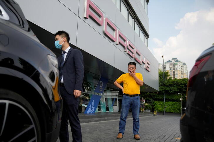 Guo Hui, whose cleaning business is owed money by China Evergrande Group, smokes a cigarette as he looks at his Porsche Cayenne he is selling to pay his debts, at a car dealership in Guangzhou, Guangdong province, China September 27, 2021. Picture taken September 27, 2021. REUTERS/Aly Song