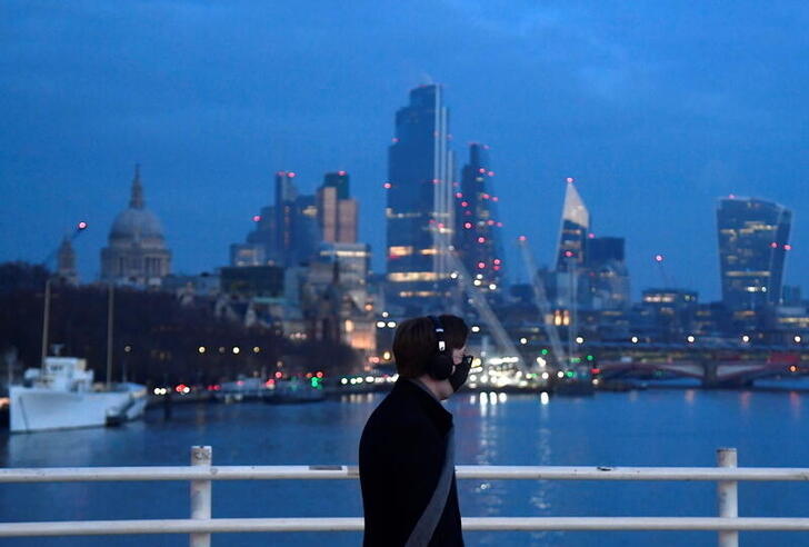 A man looks towards skyscrapers of the City of London financial district as he crosses Waterloo Bridge, amid the coronavirus disease (COVID-19) pandemic, in London, Britain, January 15, 2021. REUTERS/Toby Melville