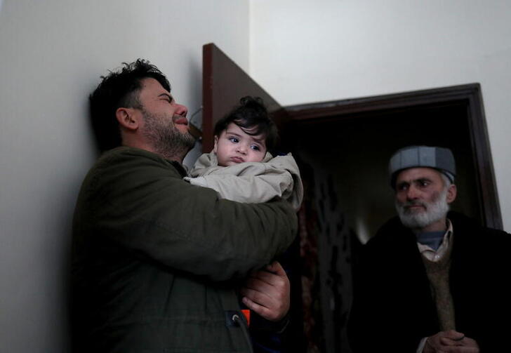 Hamid Safi, a 29-year-old taxi driver who had found baby Sohail Ahmadi in the airport, cries as he holds Sohail before handing him over to his grandfather Mohammad Qasem Razawi in Kabul, Afghanistan, January 8, 2022. Picture taken January 8, 2022. REUTERS/Ali Khara