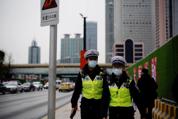 Security guards wearing protective masks walk on a street, following new cases of the coronavirus disease (COVID-19), in Shanghai, China January 17, 2022. REUTERS/Aly Song