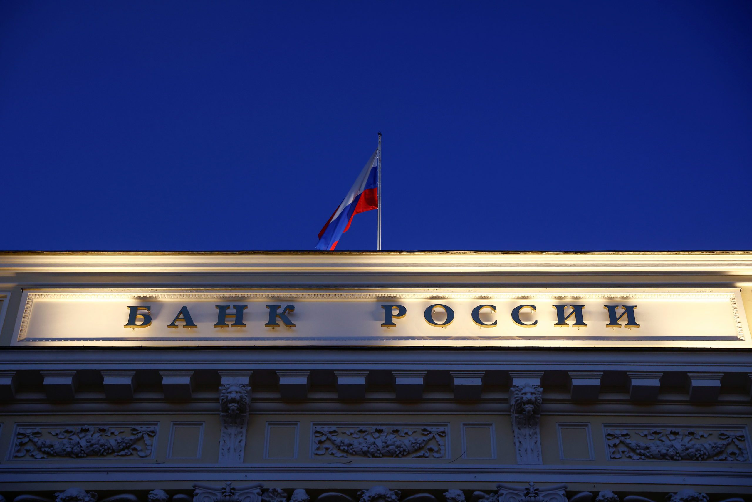 A Russian state flag flies over the Central Bank headquarters in Moscow, Russia March 29, 2021. A sign reads: 