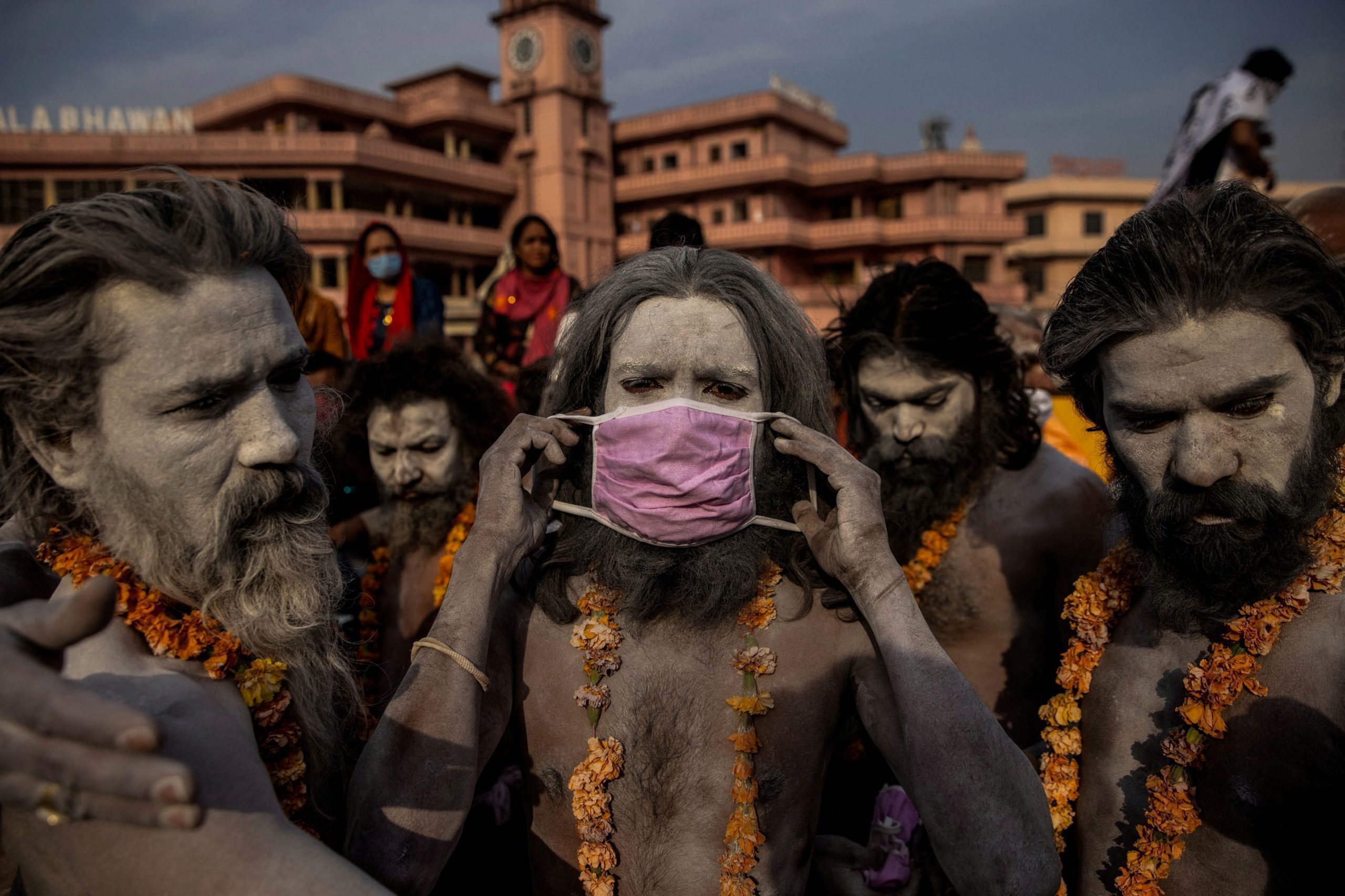 A 'Naga Sadhu,' or Hindu holy man, places a mask across his face before entering the Ganges river during the traditional Shahi Snan, or royal dip, at the Kumbh Mela festival in Haridwar, India, April 12, 2021. As COVID-19 cases and deaths exploded in India in April and May, hospitals ran so short of oxygen that many patients suffocated. REUTERS/Danish Siddiqui