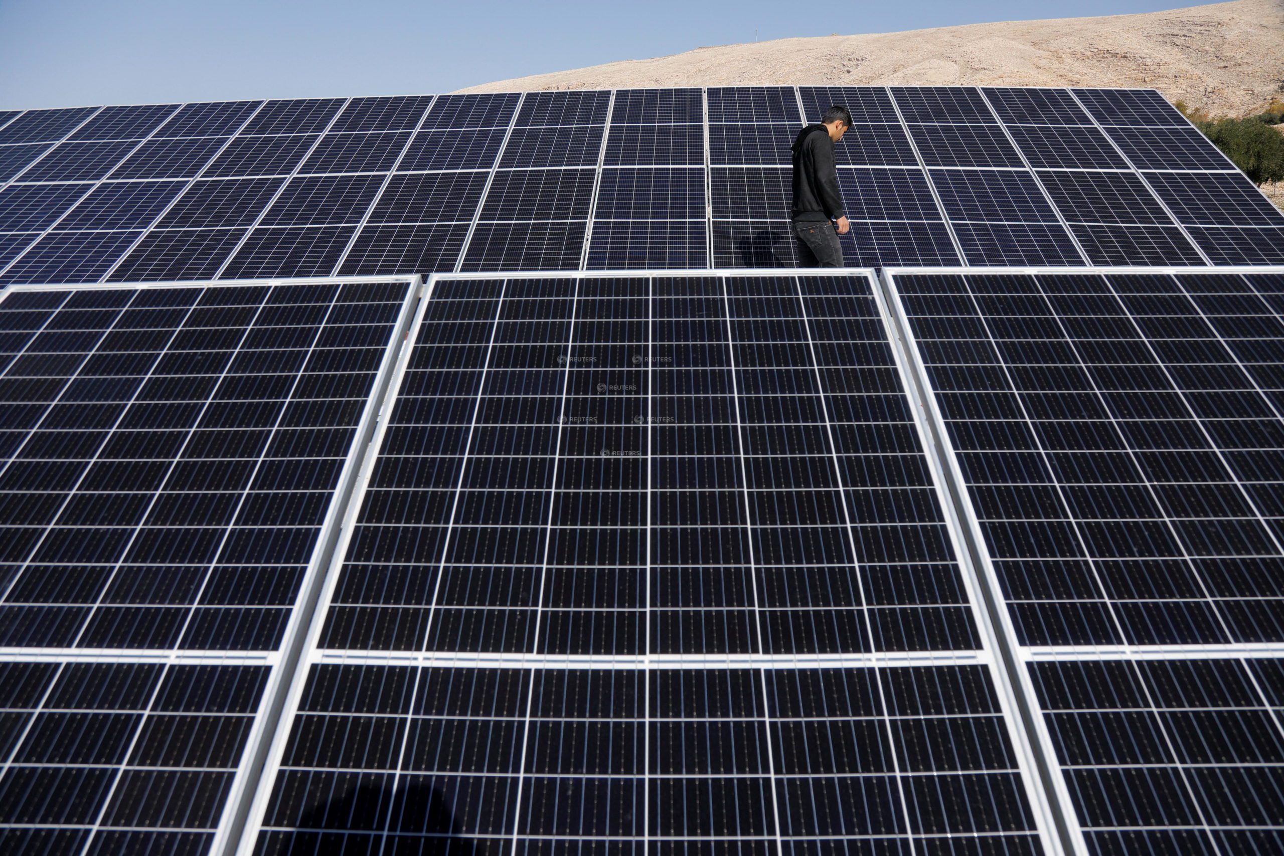 A worker walks near solar panels, which are one of the sustainable energy options that help olive farmers, in Mosul, Iraq February 2, 2022. Picture taken February 2, 2022. REUTERS/Khalid al-Mousily 