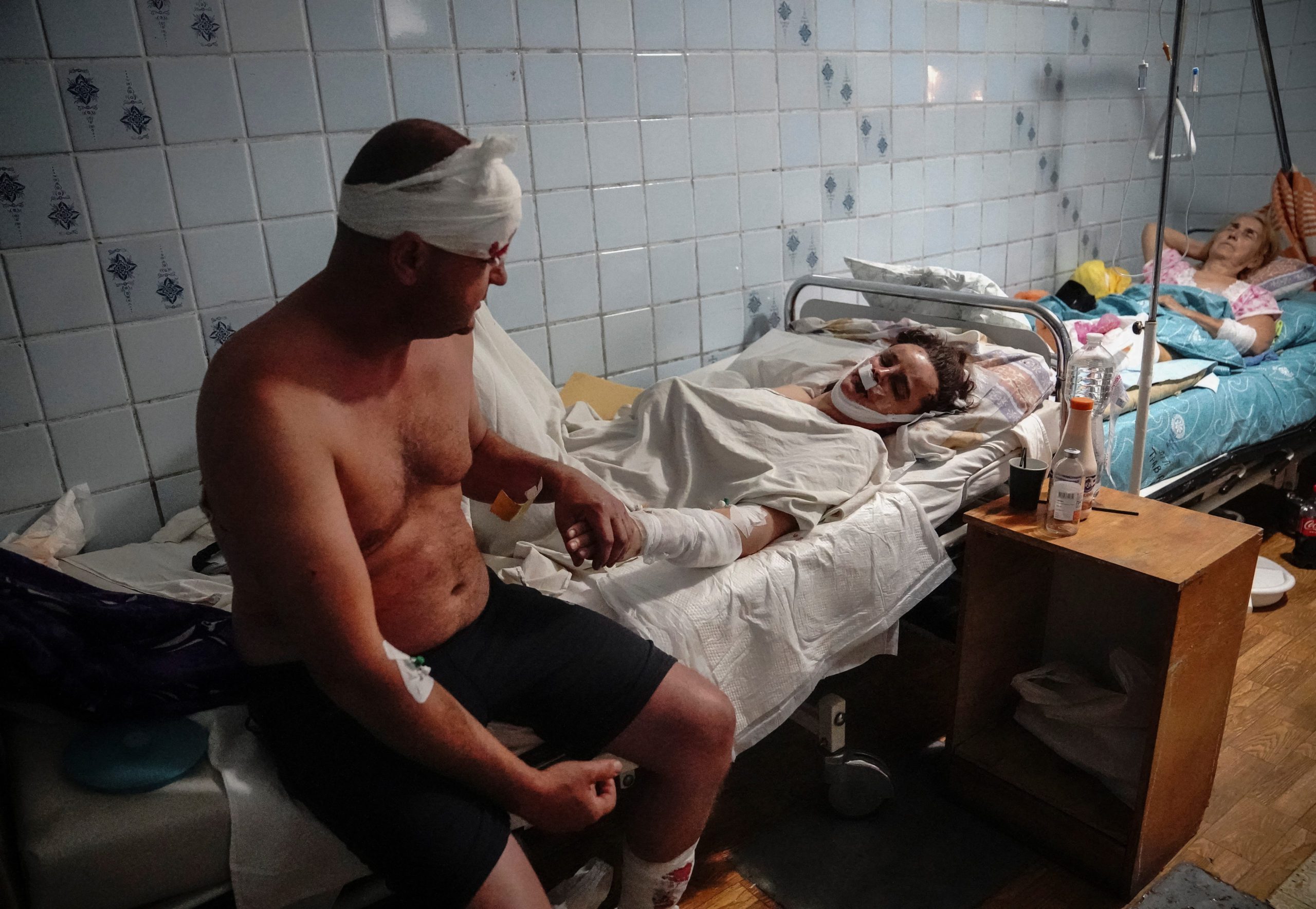 A couple wounded in a shopping mall hit by a Russian missile strike hold hands in a hospital as Russia's attack on Ukraine continues, in Kremenchuk, in Poltava region, Ukraine June 27, 2022. REUTERS/Anna Voitenko