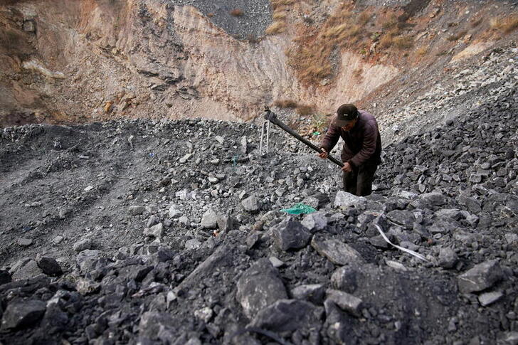 FILE PHOTO: A man sifts through dunes of low-grade coal near a coal mine in Ruzhou in China's Henan province. Picture taken November 4, 2021. REUTERS/Aly Song/File Photo