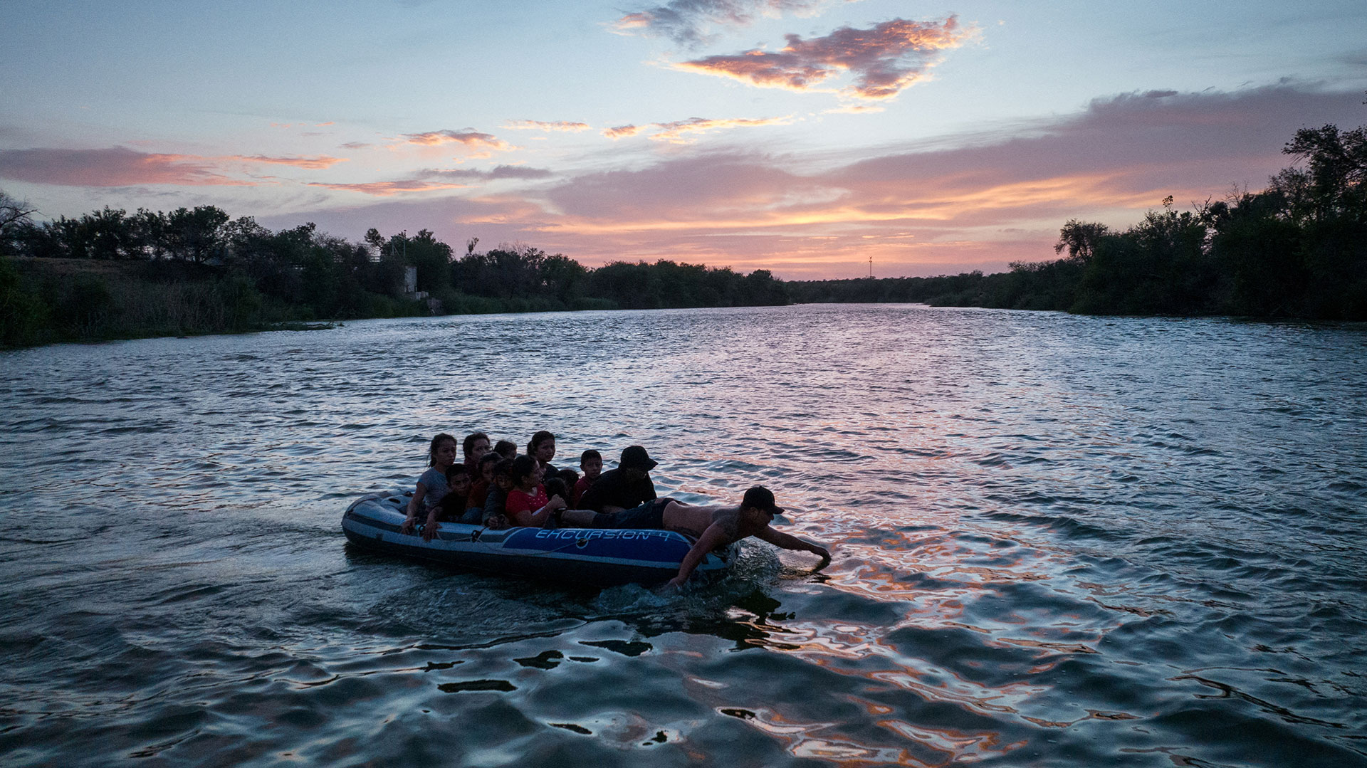 A smuggler uses his hands to paddle on a raft full of asylum seeking migrants from Central and South America across the Rio Grande river into the United States from Mexico in Roma, Texas, June 13, 2022. Picture taken June 13, 2022. Picture taken with a drone. REUTERS/Adrees Latif