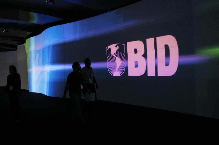 Visitors walk past a screen with the logo of Banco Interamericano de Desarrollo (BID) at the Atlapa Convention Center in Panama City March 13, 2013. Panama will be holding the annual meeting for Boards of Governors of BID, also known as the Inter-American Development Bank (IDB), from March 14 to 17. REUTERS/Carlos Jasso (PANAMA - Tags: BUSINESS LOGO)