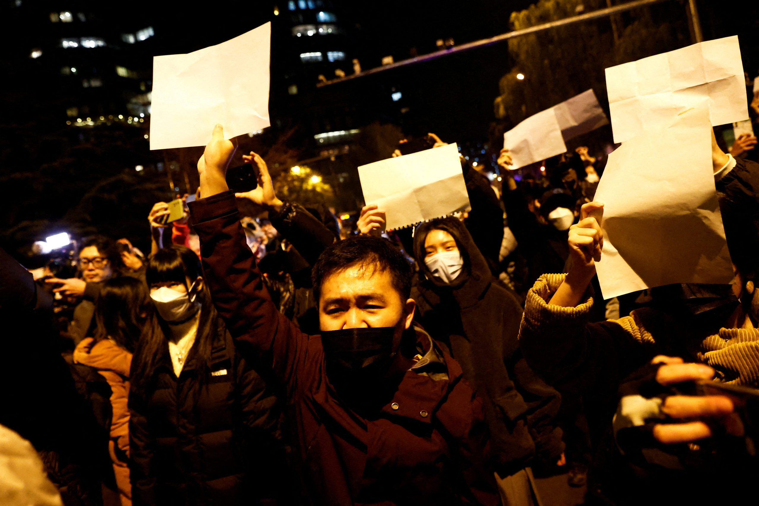 People gather for a vigil and hold white sheets of paper in protest of coronavirus disease (COVID-19) restrictions, as they commemorate the victims of a fire in Urumqi, as outbreaks of the coronavirus disease continue in Beijing, China, November 27, 2022. REUTERS/Thomas Peter      TPX IMAGES OF THE DAY