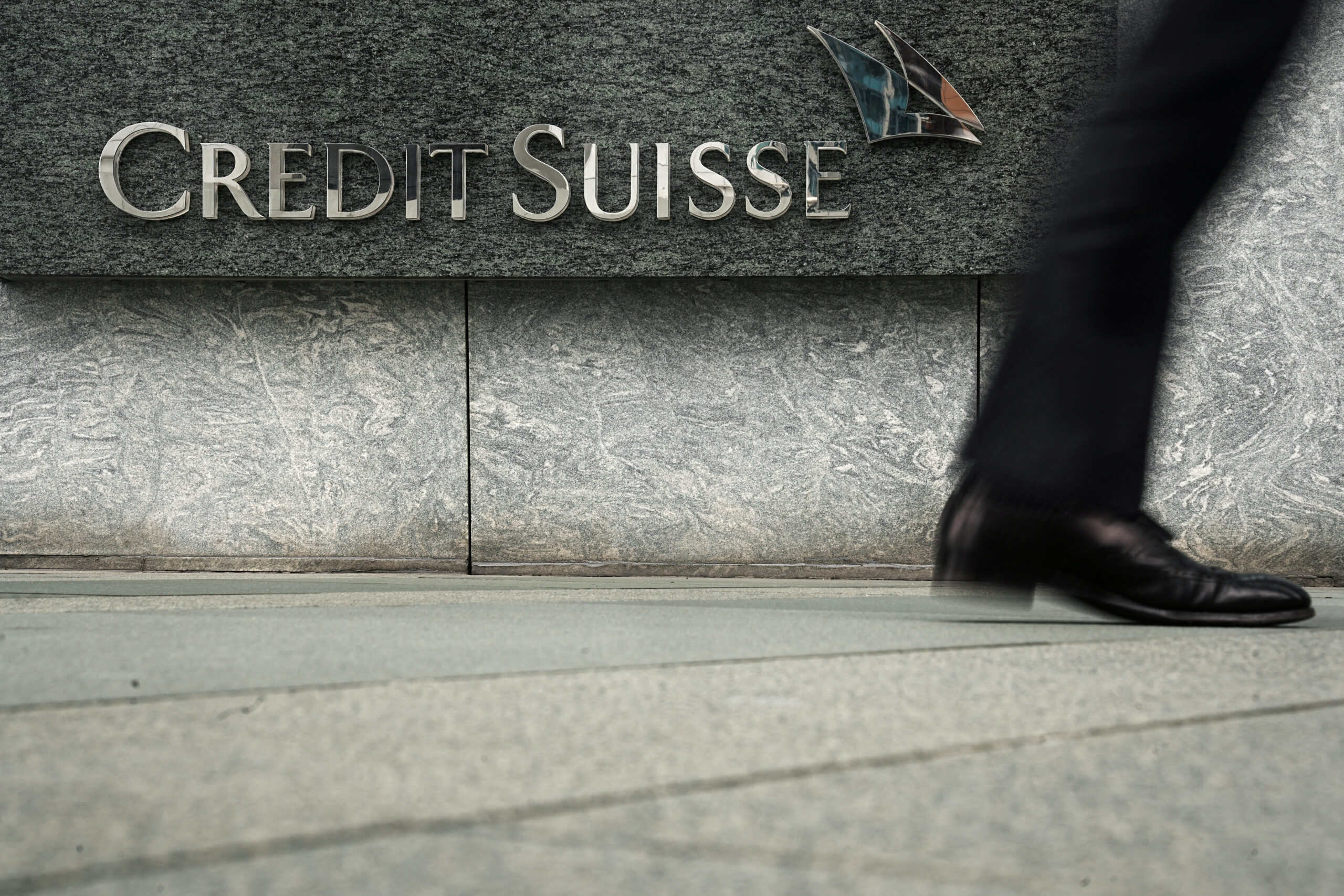 A pedestrian walks past a logo of Credit Suisse outside its office building in Hong Kong, China March 21, 2023. REUTERS/Lam Yik 